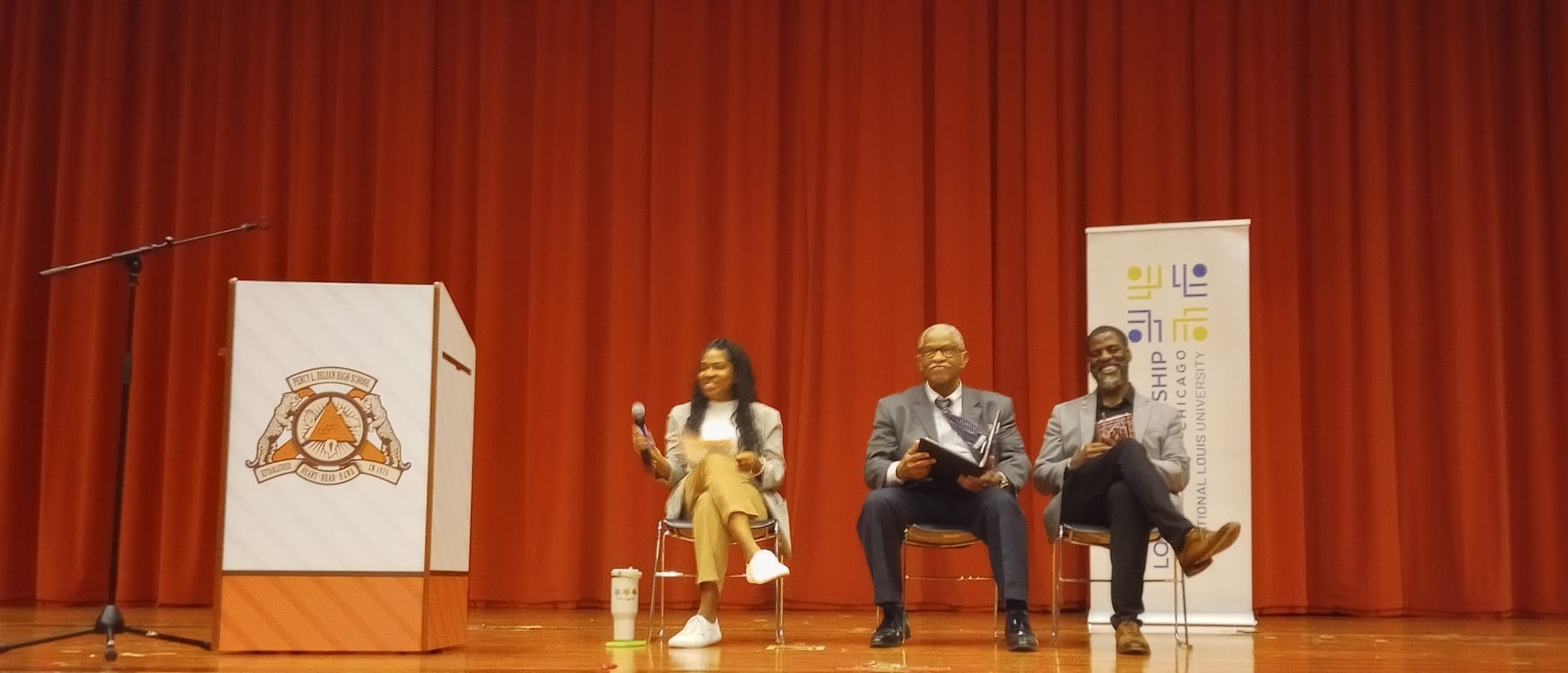 Three-person panel at Julian High School: moderator Bridget Lee speaks with board members Frank Niles Thomas and Che "Rhymefest" Smith.
