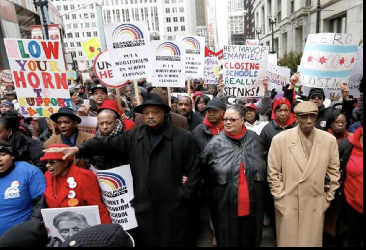 Rev. Jesse Jackson, center, dressed in black and wearing a black fedora, marches arm in arm with CTU President Karen Lewis to protest school closings.