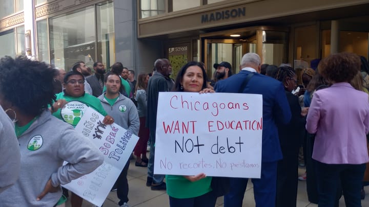 A women holds up a sign saying, "Chicagoans want education not dbet. No recortes. No prestamos."