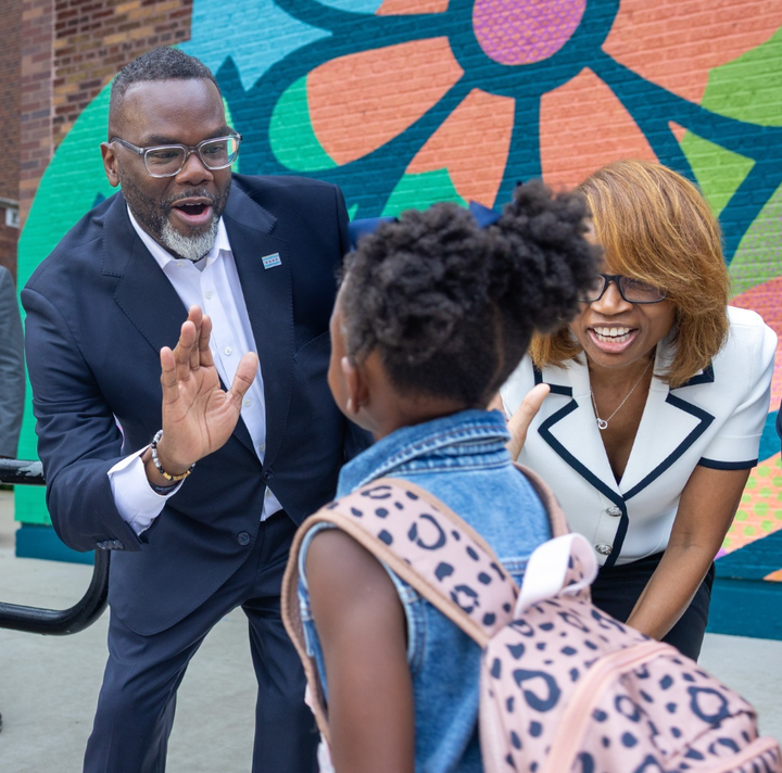 Chicago Mayor Brandon Johnson (left) and Chicago Public Schools Interim Superintendent/CEO Macquline Kinghold up their palms to high-five a young girl.